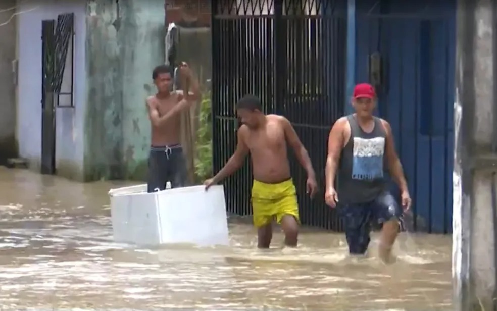 Morador usa geladeira para conseguir visitar casa alagada após enchente no sul da Bahia